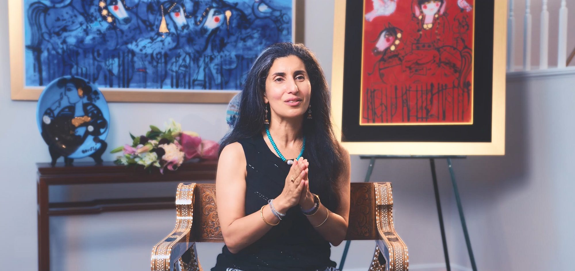 Maryam Ovissi seated in front of her artwork